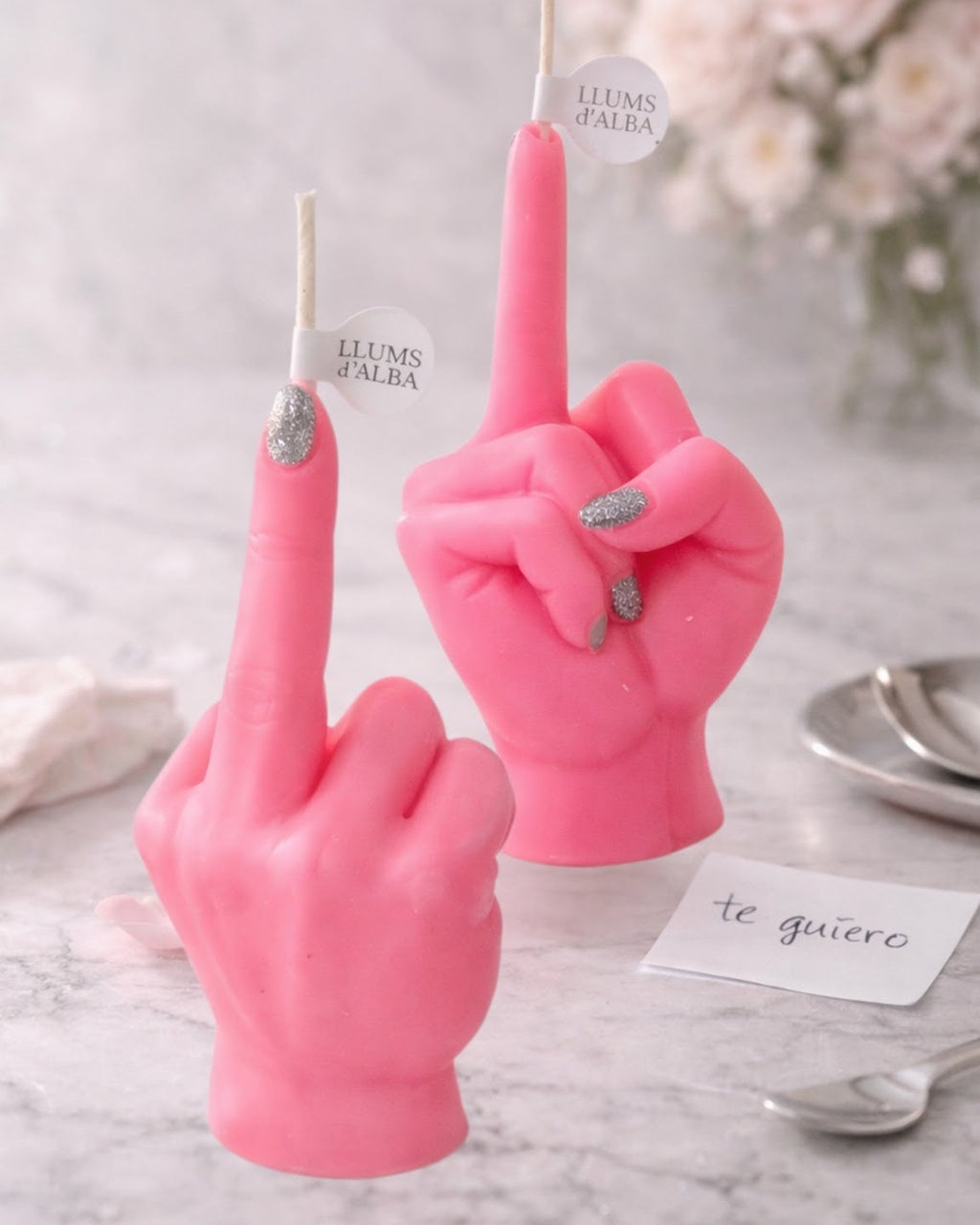 Dos velas FAKOV rosas con uñas plateadas sobre una mesa de mármol.